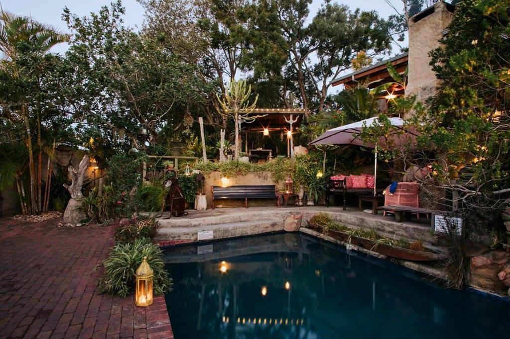 Gemütlicher Garten mit Pool, Sitzbereichen, Laternen und Terrasse bei Dämmerung