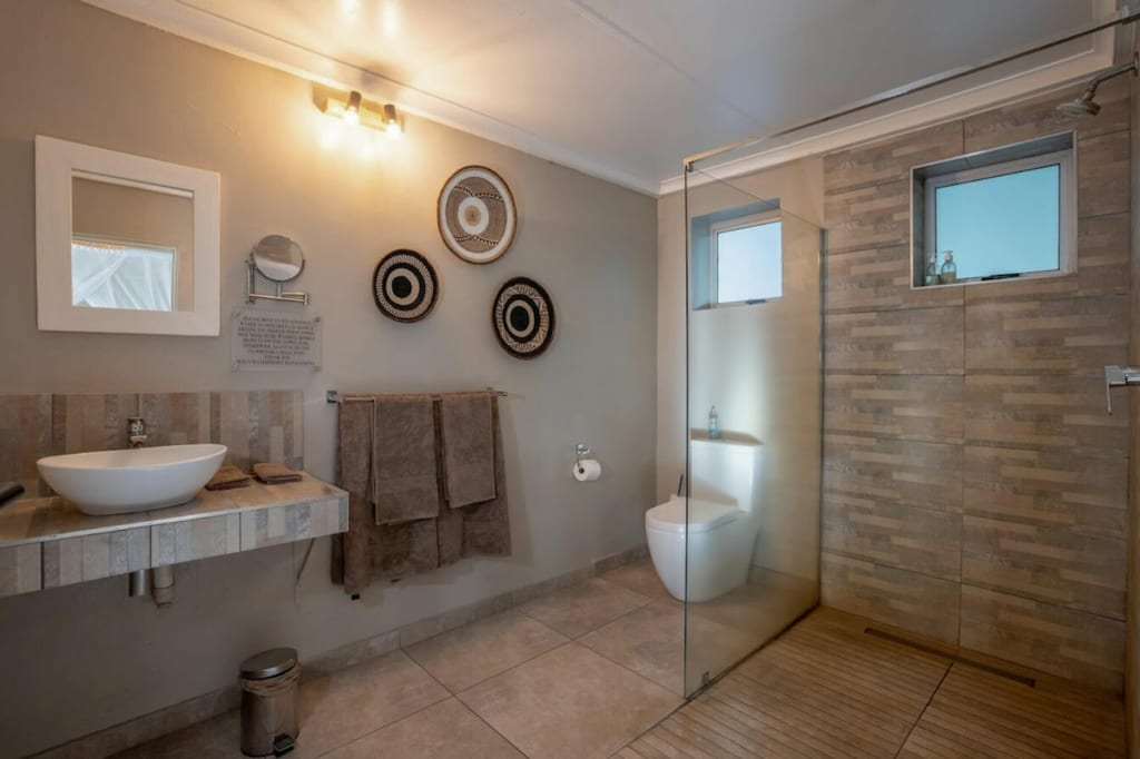 Modernes Badezimmer mit begehbarer Dusche, Aufsatzwaschbecken, WC und aufgehängten Handtüchern.