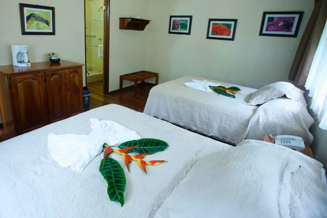 Hotelzimmer mit zwei Einzelbetten, weißen Bettdecken und tropischen Blumenarrangements.