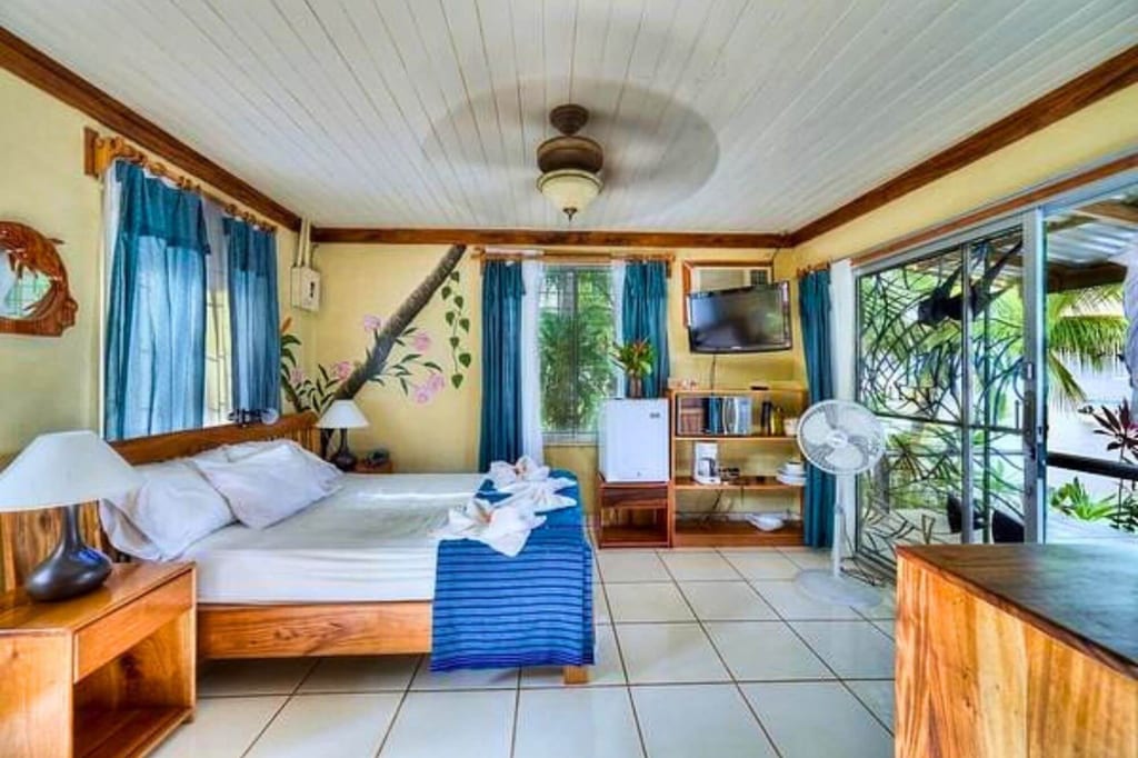 Helles Schlafzimmer mit Doppelbett, Holzmöbeln und Schiebetür zum begrünten Balkon