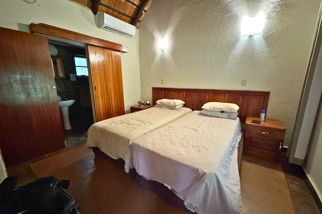 Gästezimmer mit zwei zusammengestellten Einzelbetten, Nachttischen und Zugang zu einem kleinen Bad.