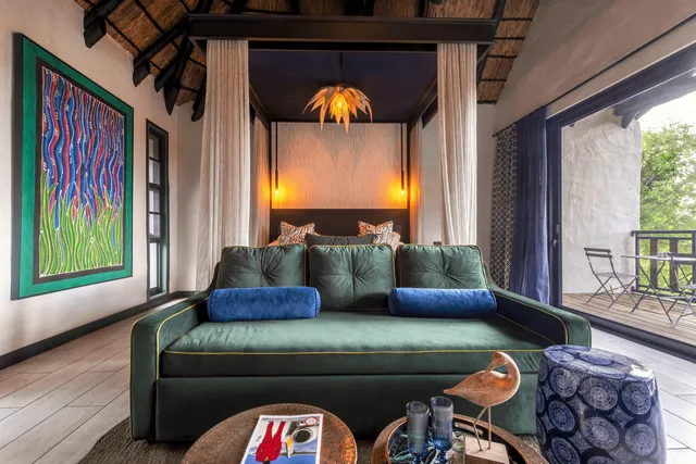 Innenraum einer Lodge-Suite mit grünem Samtsofa, Himmelbett und offenem Balkon bei Tageslicht