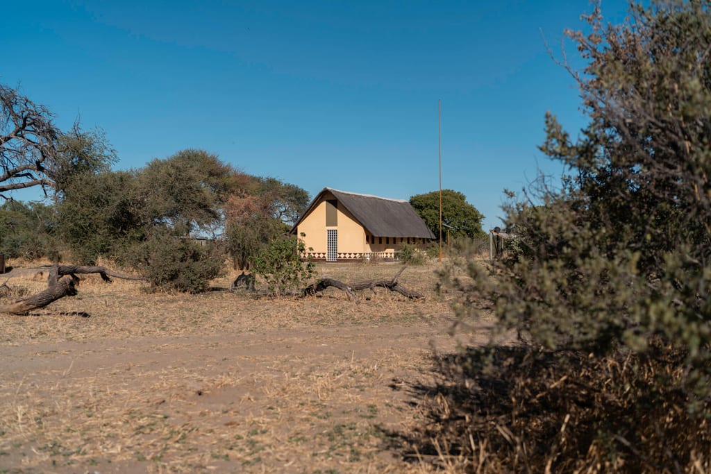 Gelbes Strohdachhaus in trockener Savannenlandschaft unter klarem blauem Himmel
