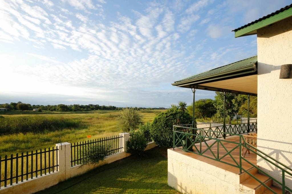 Veranda mit Blick auf weite Graslandschaft und Zaun bei warmem Spätnachmittagslicht.