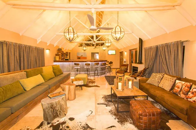 Weitwinkelaufnahme einer gemütlichen Lodge-Lounge mit Sofas, Bar und warmem Licht.