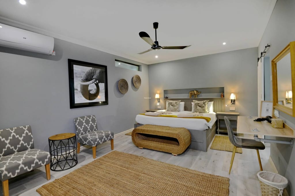 Modernes Hotelzimmer mit Doppelbett, geflochtener Bank und Wandbild eines Elefanten.