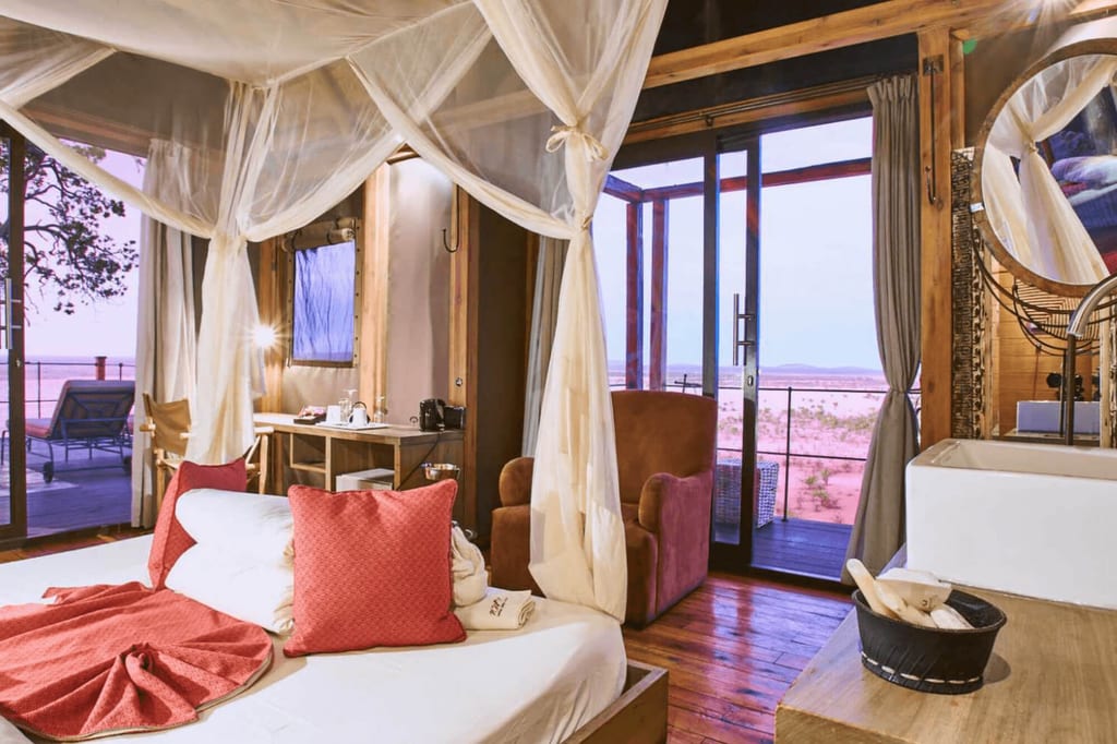 Gemütliches Safari-Lodges-Zimmer mit Himmelbett, Veranda und weitem Ausblick bei warmem Abendlicht.