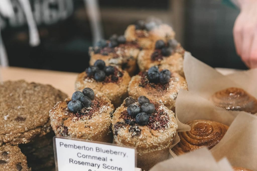Nahaufnahme von Blaubeer-Scones mit frischen Blaubeeren auf einer Bäckerei-Theke.