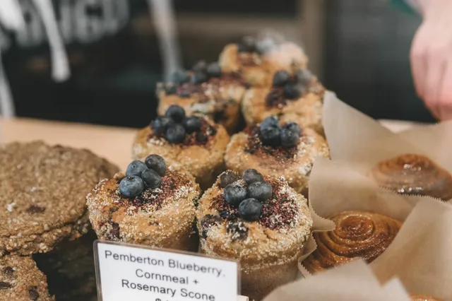 Nahaufnahme von Blaubeer-Scones mit frischen Blaubeeren auf einer Bäckerei-Theke.
