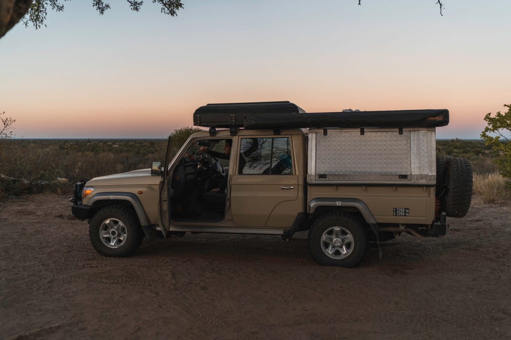 Seitenansicht eines ausgebauten Pickup-Campers bei Dämmerung vor weiter, flacher Landschaft.