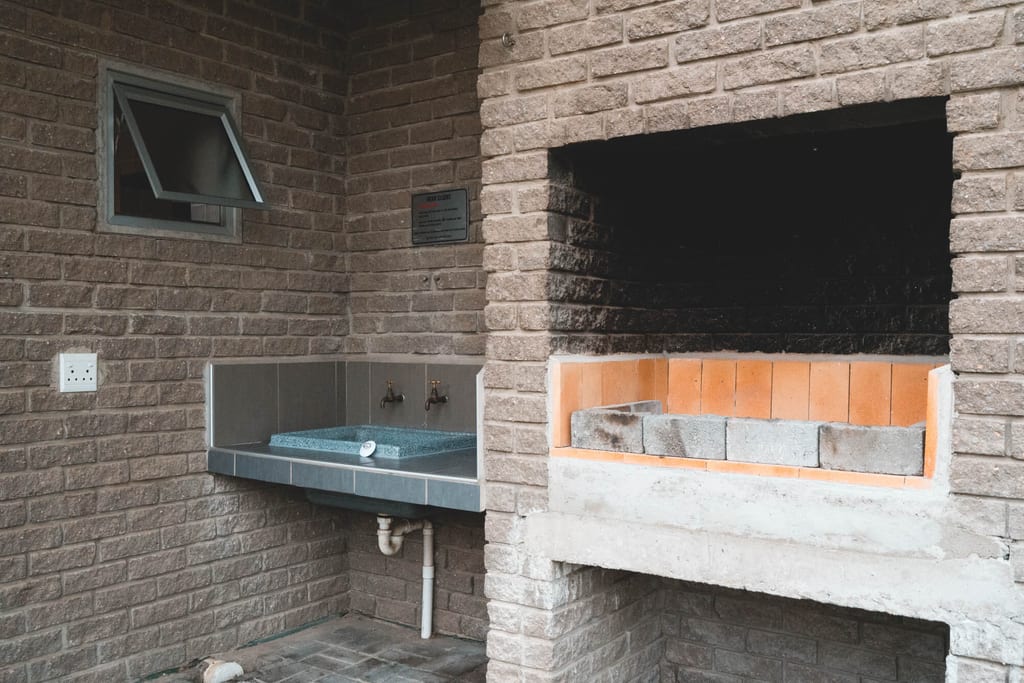 Gemauerte Außenküche mit eingebautem Grill und gefliestem Spülbecken, frontal aufgenommen.
