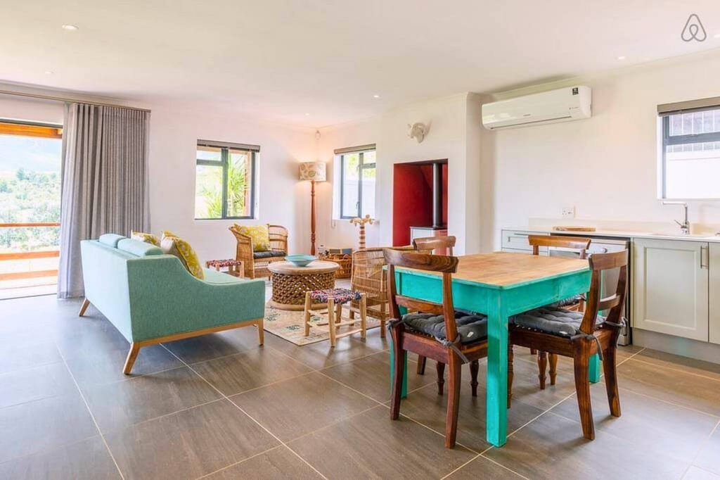 Helles offenes Wohn- und Esszimmer mit türkisem Tisch und Sofa, Tageslicht durch Fenster