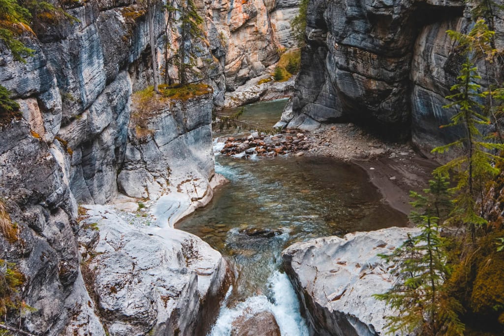 Blick von oben in eine enge Schlucht mit klarem Gebirgsbach zwischen geglätteten Felswänden