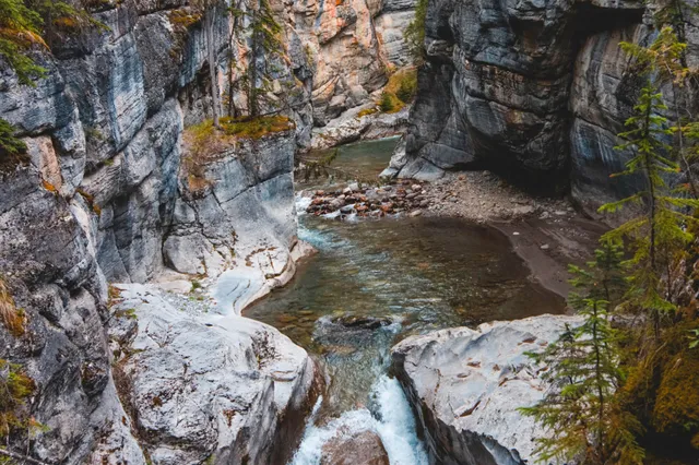 Blick von oben in eine enge Schlucht mit klarem Gebirgsbach zwischen geglätteten Felswänden