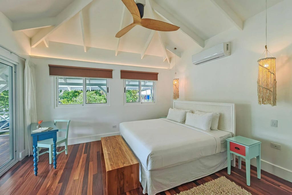 Helles Schlafzimmer mit Doppelbett, Holzfußboden und Fensterblick auf Grün