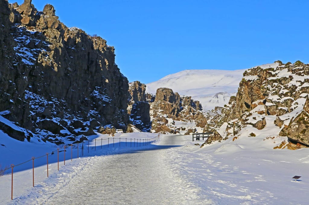 Verschneiter Felsspalt mit eisbedecktem Weg, steilen Felswänden und klarem Blau am Himmel