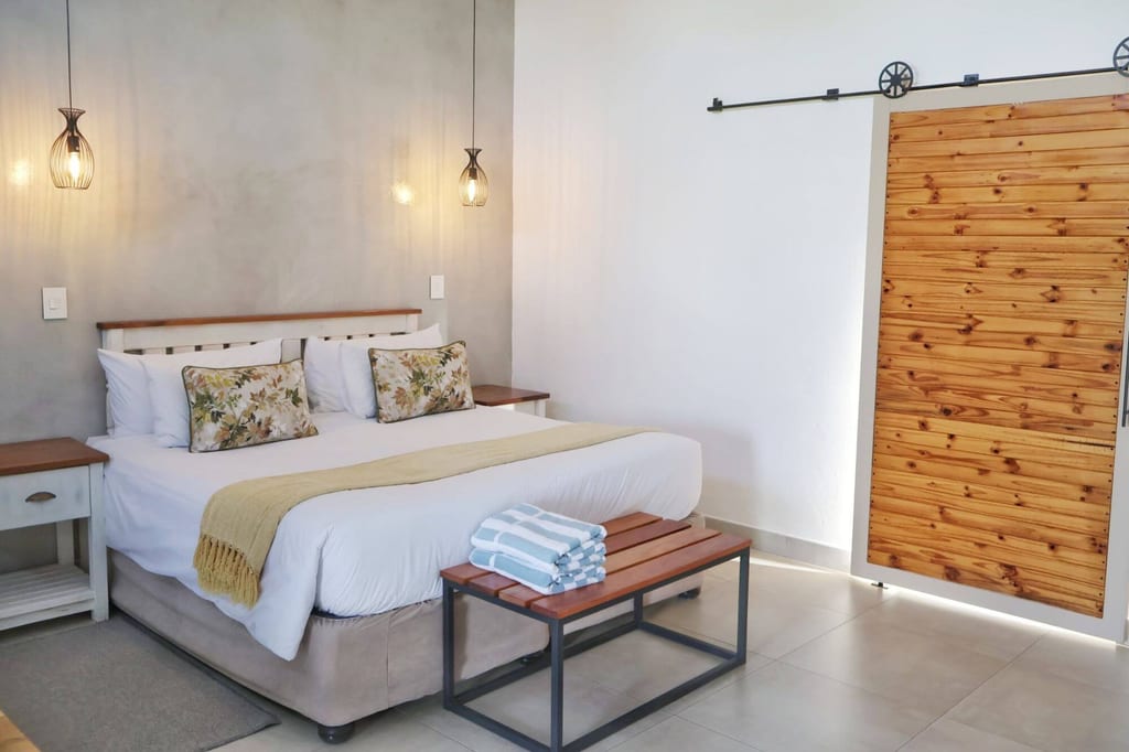 Helles Schlafzimmer mit Doppelbett, Pendelleuchten und Holz-Schiebetür, Tageslicht von rechts