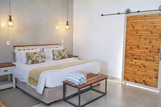 Helles Schlafzimmer mit Doppelbett, Pendelleuchten und Holz-Schiebetür, Tageslicht von rechts