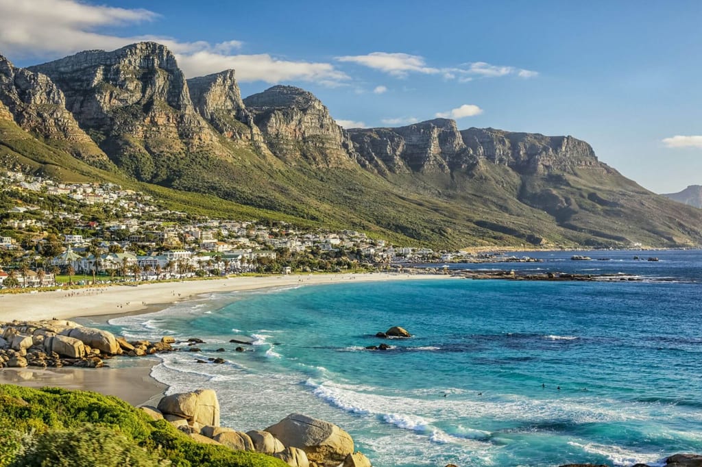 Panoramablick auf Strand, türkisblaues Meer und steile Felsformationen im warmen Nachmittagslicht