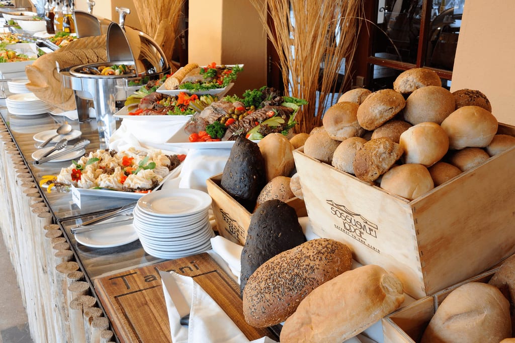 Buffet mit verschiedenen Broten, Brötchen sowie Schalen mit Salaten und warmen Speisen.