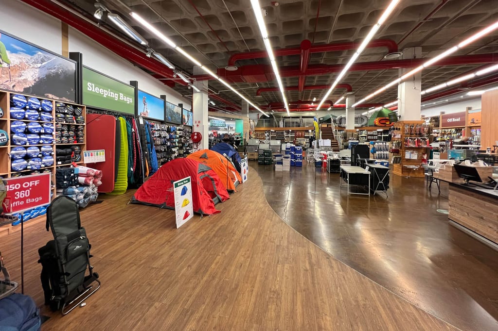Innenaufnahme eines Outdoor-Fachgeschäfts mit aufgebauten Zelten und Regalen voller Campingausrüstung