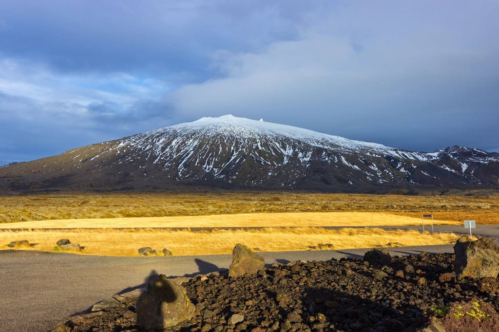 Schneebedeckter Berg auf der Snæfellsnes-Halbinsel, vulkanische Felsen und warmes Abendlicht