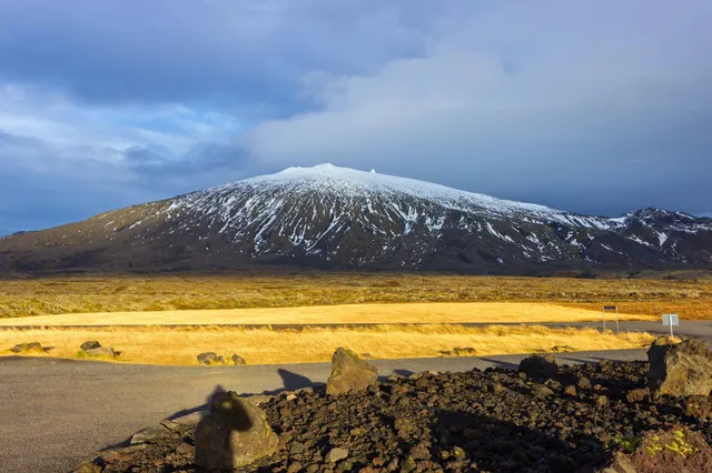 Schneebedeckter Berg auf der Snæfellsnes-Halbinsel, vulkanische Felsen und warmes Abendlicht