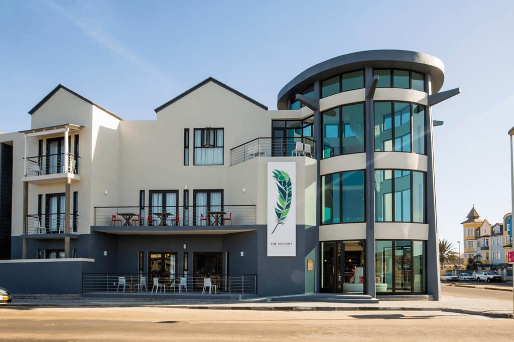 Modernes Gebäude mit rundem Glasturm, Balkonen und Terrasse bei sonnigem Tageslicht