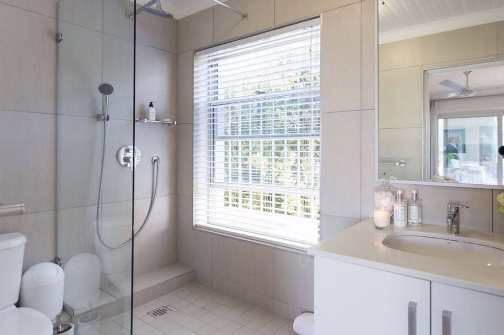 Helles modernes Badezimmer mit Glasdusche, Fensterjalousien und Waschtisch