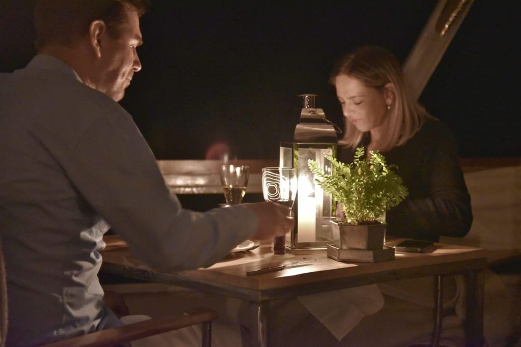 Zwei Personen beim Abendessen an einem Tisch mit Laterne und Topfpflanze, warme Lichtstimmung