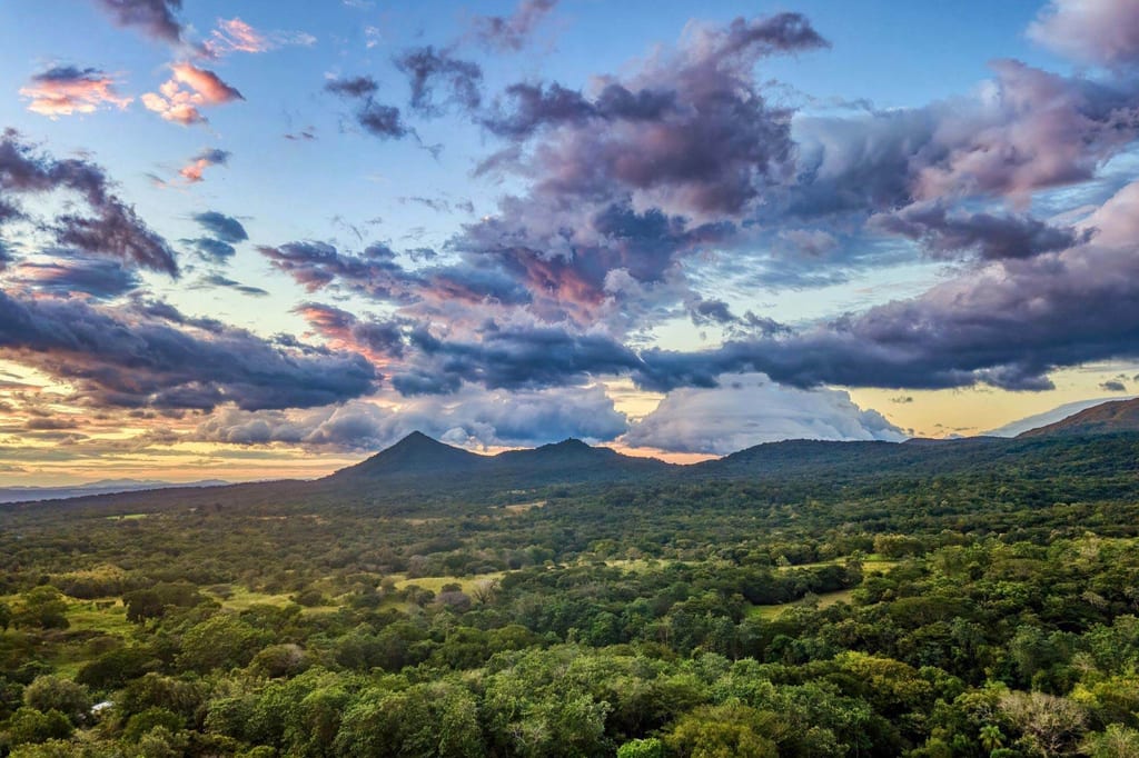 Panoramablick auf Vulkan- und Waldlandschaft im Rincón de la Vieja bei dramatischem Abendhimmel.