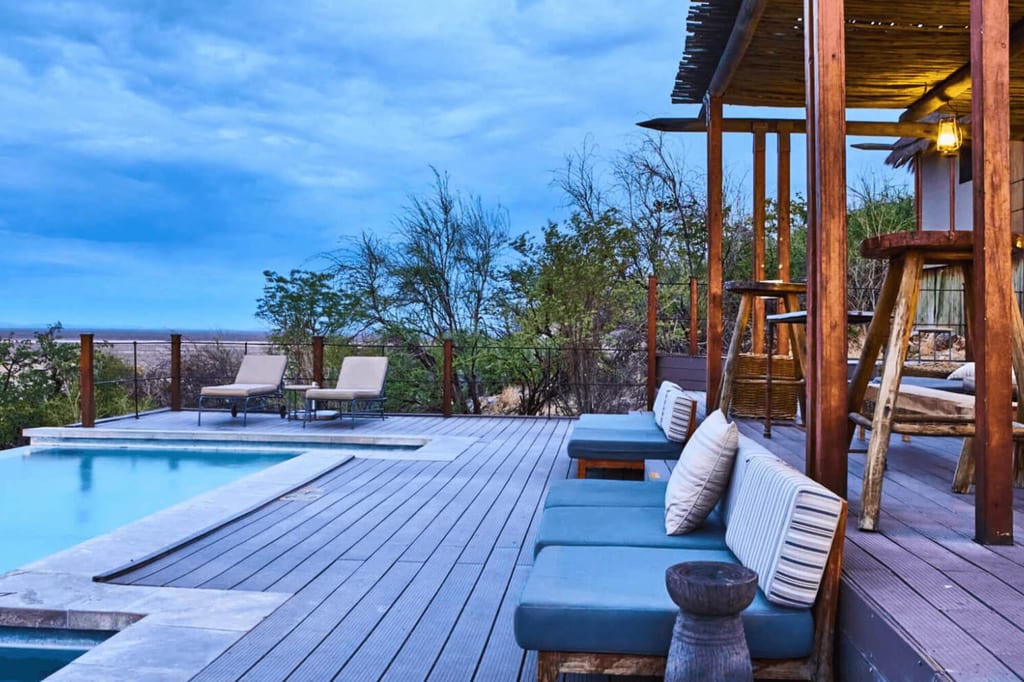 Terrasse mit Pool, Liegen und überdachter Sitzecke vor bewölktem Himmel
