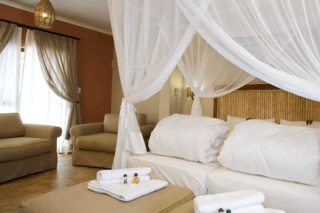 Gemütliches Hotelzimmer mit weißem Moskitonetz über dem Bett und gefalteten Handtüchern