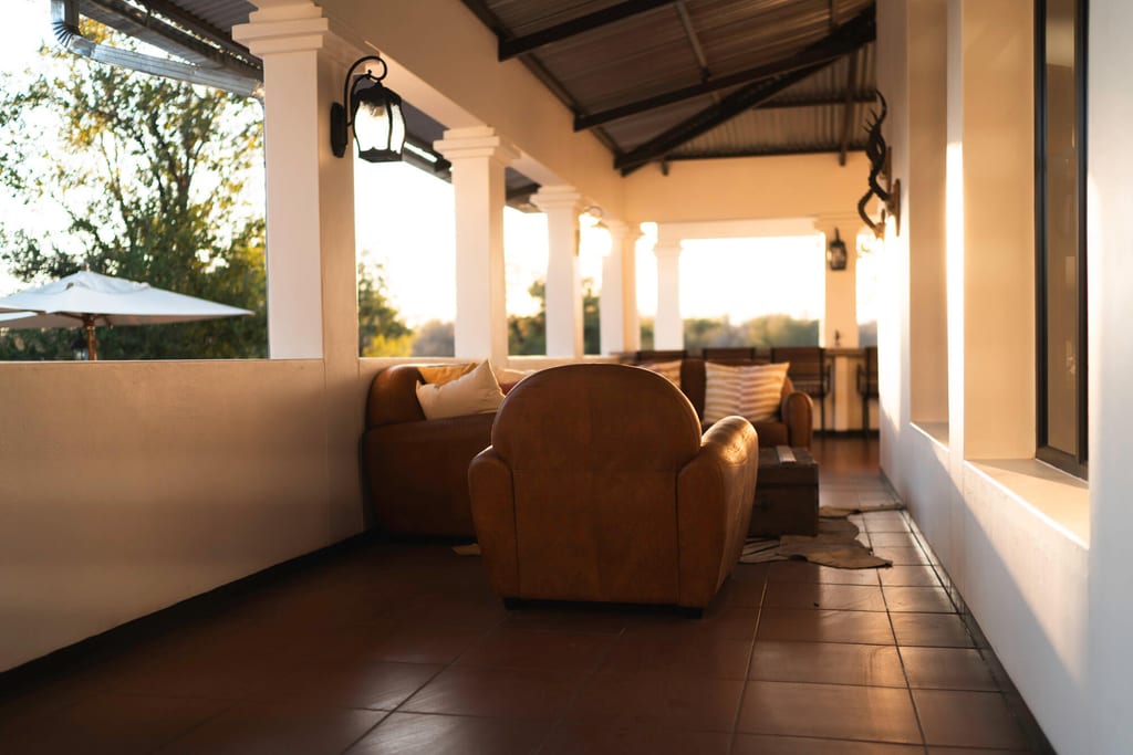 Überdachte Terrasse mit braunen Ledersofas im warmen Abendlicht