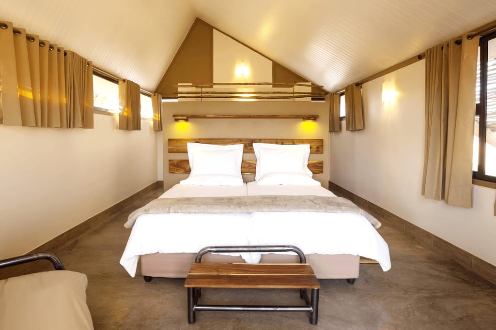 Frontalansicht eines gemütlichen Hotelzimmers mit Doppelbett, Holzdetails und warmem Licht.
