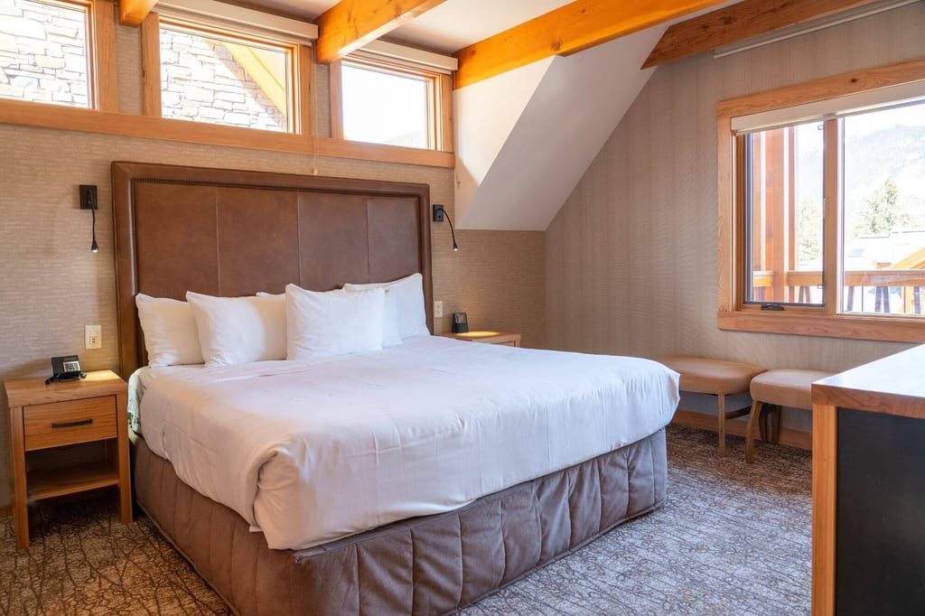 Helles Hotelzimmer mit großem Bett, Fensterblick und warmen Holzakzenten