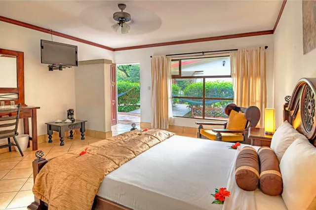 Gemütliches, sonnendurchflutetes Zimmer mit Doppelbett, Sessel und Blick auf Terrasse und Garten