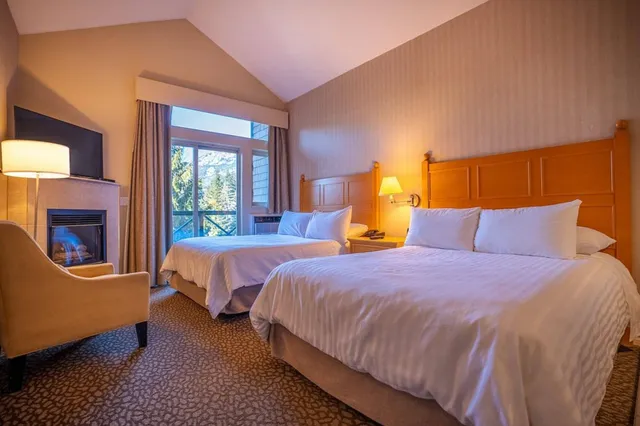 Gemütliches Doppelzimmer mit zwei Betten, Kamin und Bergblick durch die Balkontür.