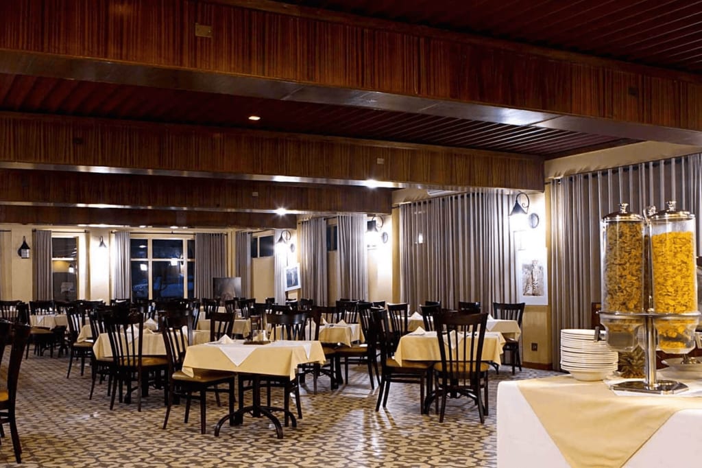 Großer leerer Speisesaal mit gedeckten Tischen und Buffetspendern im Vordergrund.