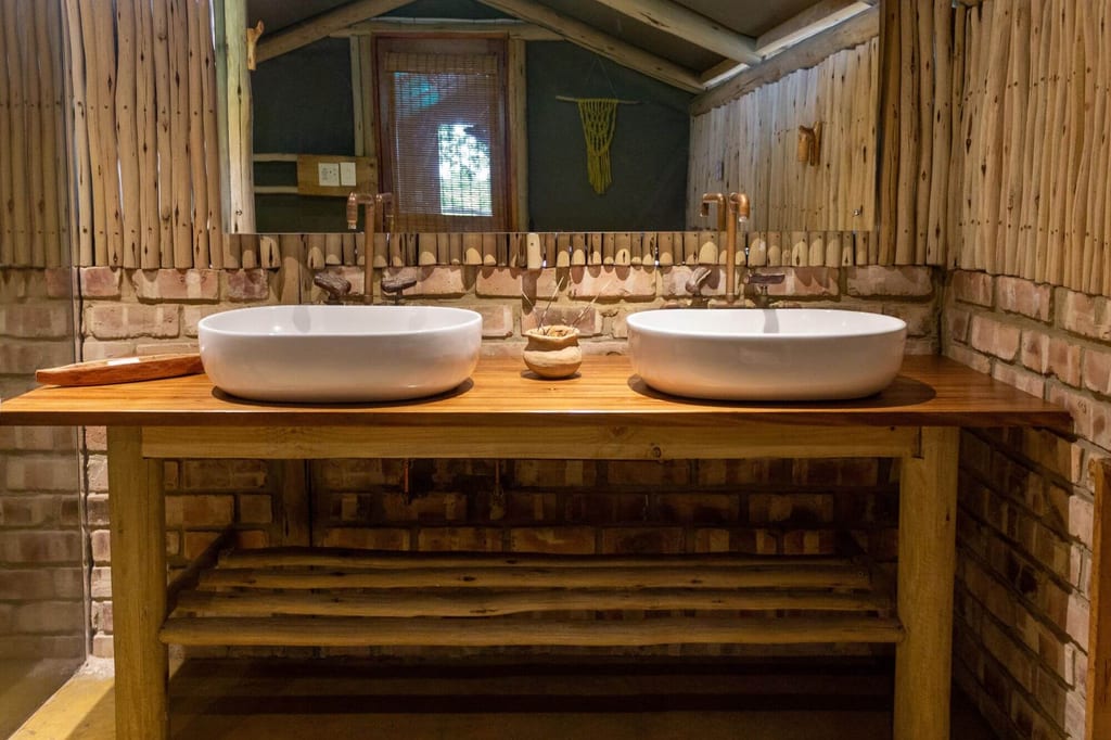 Rustikales Badezimmer mit zwei weißen Aufsatzwaschbecken auf Holzplatte und Mauerwerkswand