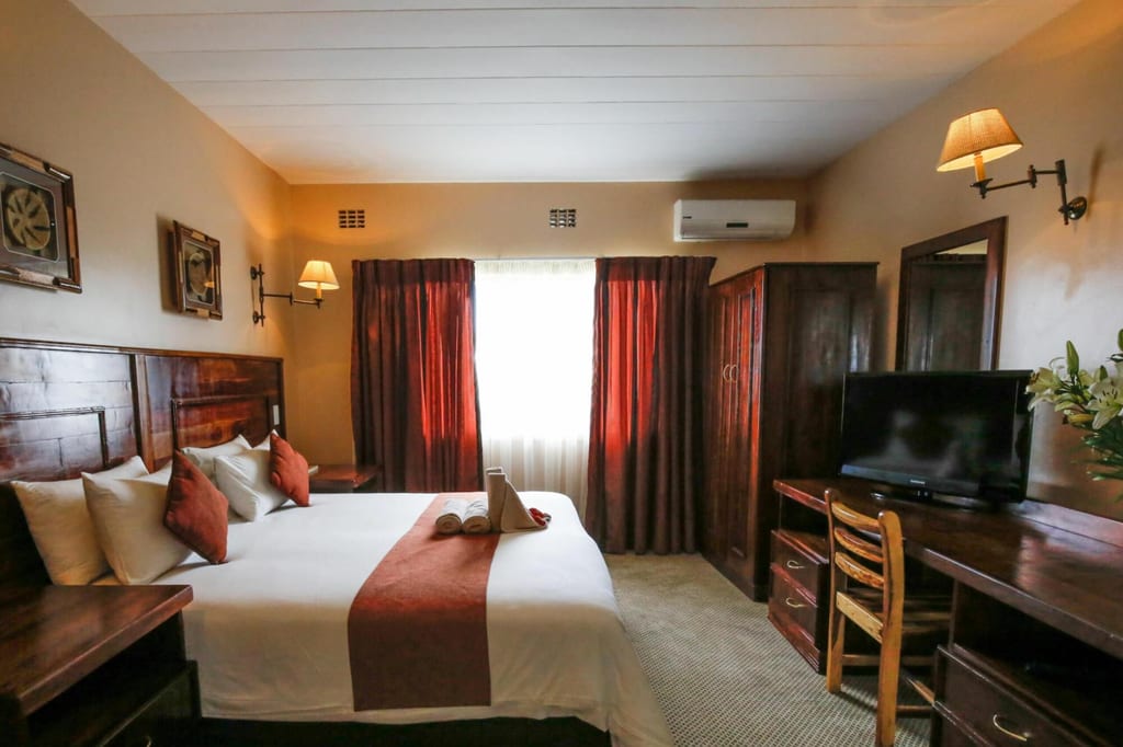 Gemütliches Hotelzimmer mit Doppelbett, Schreibtisch, Fernseher und geschlossenen Vorhängen