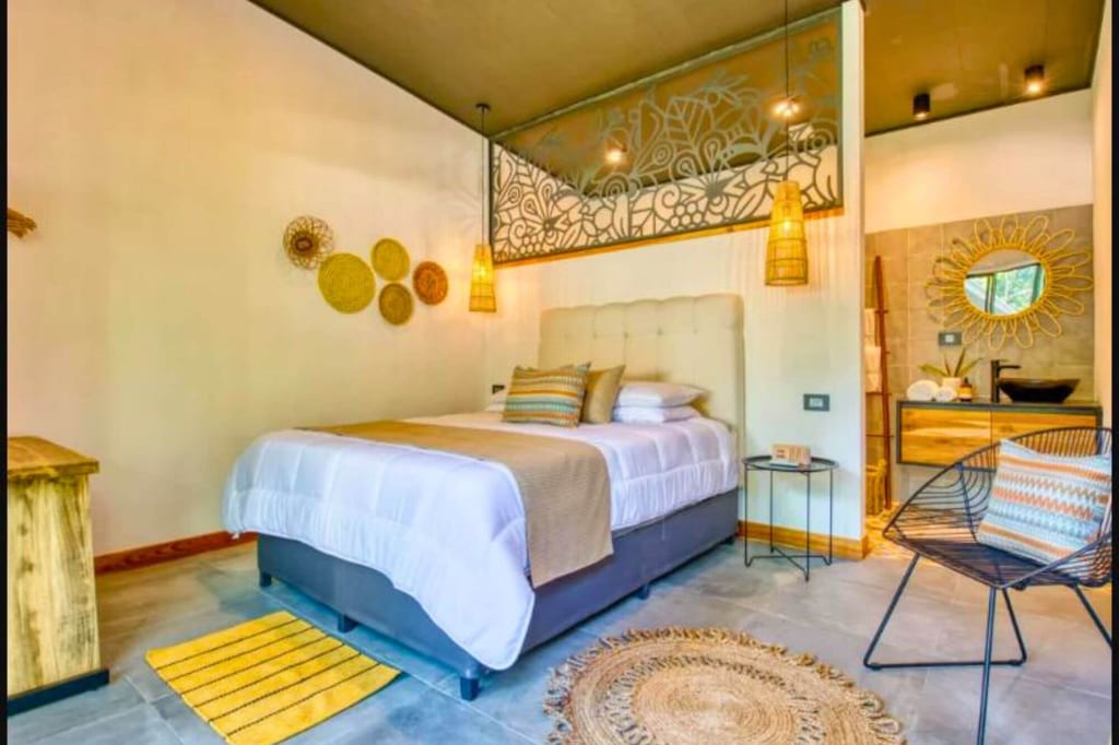 Boho-Schlafzimmer mit großem Bett, Rattan-Deko, gewebten Teppichen und warmem Licht.