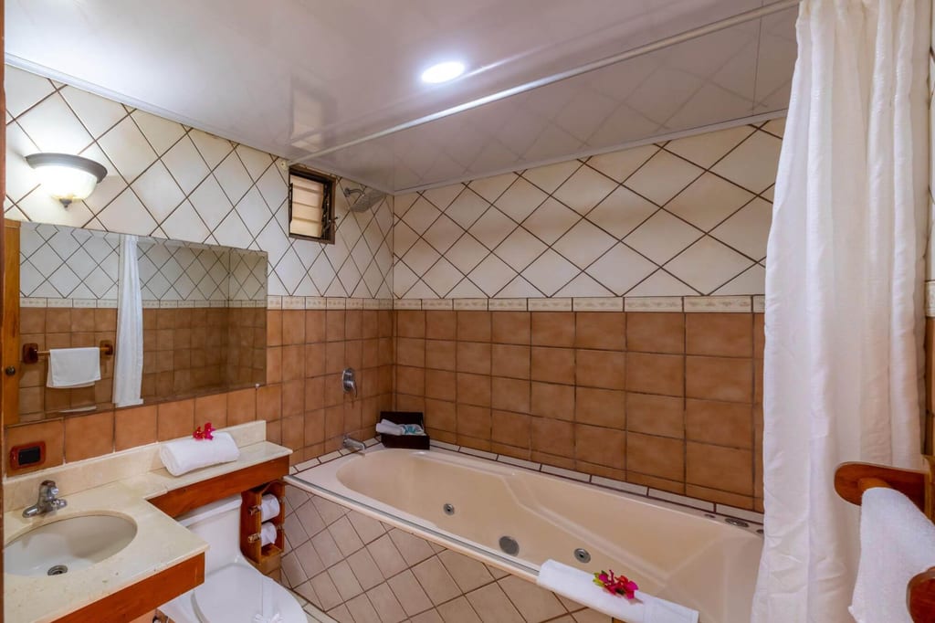 Innenaufnahme eines gefliesten Badezimmers mit Whirlpool-Badewanne, Waschbecken und Handtüchern