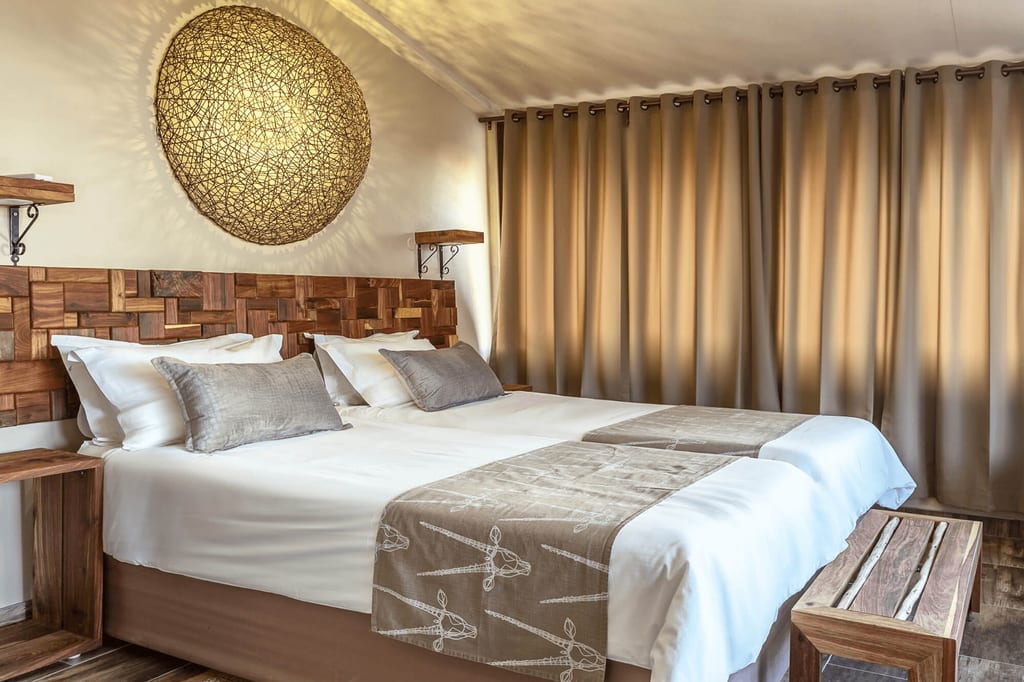 Gemütliches Hotelzimmer mit großem Doppelbett, hölzernem Kopfteil und runder Wandlampe