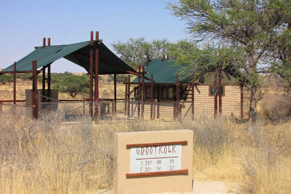 Kleines Safari-Camp mit Zeltunterkünften und Schild "GROOTKOLK" in trockenem Grasland bei Tageslicht