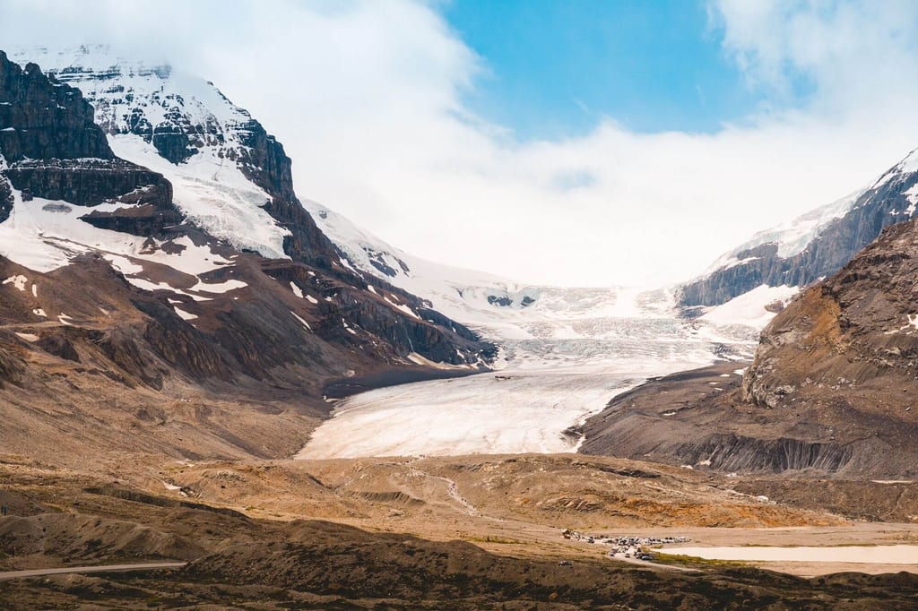 Panoramablick auf einen breiten Gletscher zwischen schroffen Bergen unter klarem Himmel.