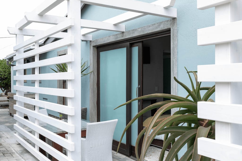 Terrasse mit weißer Pergola, hellem Schiebe-Glas und großer sukkulenter Pflanze