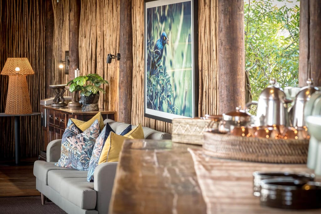 Gemütliche Lounge mit Sofa, Holzwand, gerahmtem Vogelfoto und warmem Tageslicht