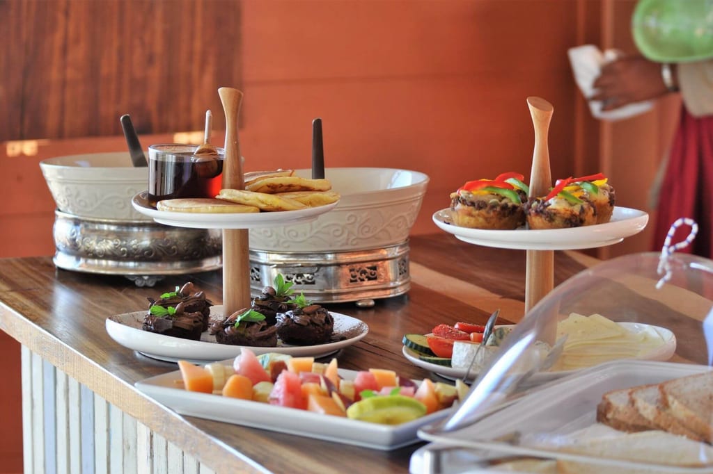 Nahaufnahme eines Frühstücksbuffets mit Kuchen, Muffins, Obst, Käse und Brot auf einem Holztresen