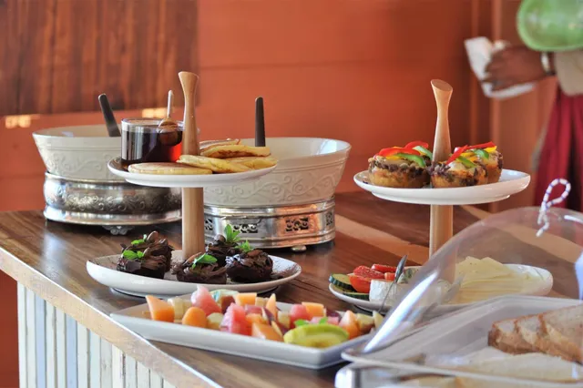 Nahaufnahme eines Frühstücksbuffets mit Kuchen, Muffins, Obst, Käse und Brot auf einem Holztresen